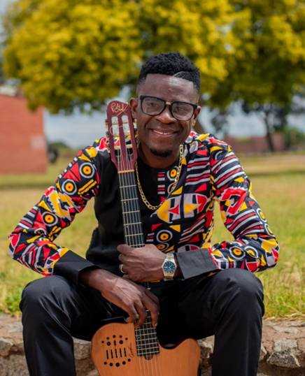 A person sitting on the ground holding a guitar

AI-generated content may be incorrect.